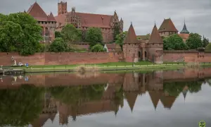 Potężny zamek w Malborku odbija się w wodzie. Sprawdź zamek w Malborku cennik i zaplanuj wizytę w tym historycznym miejscu.