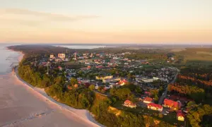 Widok z lotu ptaka na Jarosławiec: plaża, klify, zabudowania i morze o zachodzie słońca.
