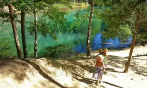 Dwie dziewczynki w słomkowych kapeluszach idą ścieżką nad turkusowe jezioro. Idealne miejsce, gdzie w góry z dzieckiem 2 letnim na spacer.