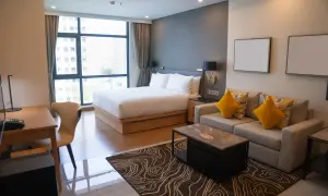 Nowoczesny pokój hotelowy z łóżkiem, sofą i biurkiem, widok z okna na miasto.