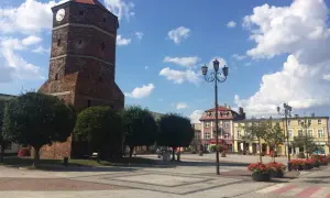 Wieża zegarowa w Barcinie góruje nad rynkiem, otoczonym kolorowymi kamienicami.