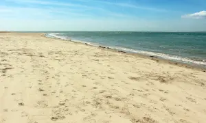 Pusta plaża Ulinia z licznymi śladami na piasku, spokojne morze i błękitne niebo.