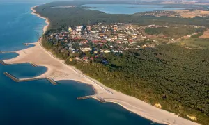 Widok z lotu ptaka na nadmorską miejscowość z plażą, lasem i zatoczkami. Jezierzany atrakcje czekają!