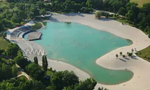 Zagrzeb plaża z turkusową wodą i piaszczystymi brzegami, otoczona zielenią. Widoczne amfiteatr i drewniany pomost.