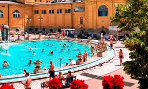 Budapeszt termy cennik: Słoneczny dzień w basenie z ludźmi relaksującymi się w wodzie.