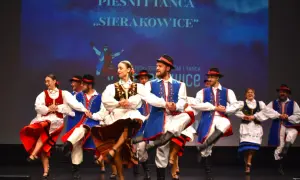 Tancerze w strojach ludowych podczas wydarzeń w Sierakowicach. Kolorowe stroje i dynamiczne ruchy na scenie.