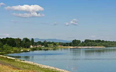 Spokojne jezioro otmuchowskie z łodziami przy brzegu, otoczone zielenią. Idealne miejsce na wypoczynek i odkrywanie atrakcji.