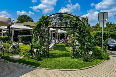Letnie popołudnie w jednej z warszawskich restauracji z ogródkiem. Goście relaksują się na leżakach wśród zieleni.