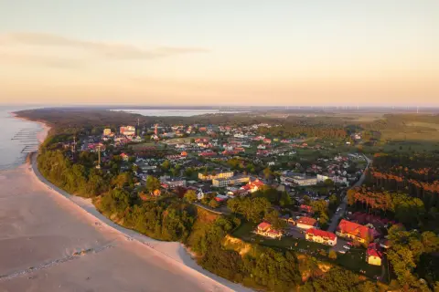 Widok z lotu ptaka na Jarosławiec: plaża, klify, zabudowania i morze o zachodzie słońca.