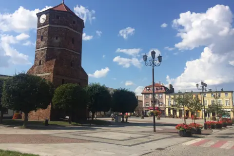 Wieża zegarowa w Barcinie góruje nad rynkiem, otoczonym kolorowymi kamienicami.