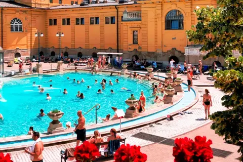 Budapeszt termy cennik: Słoneczny dzień w basenie z ludźmi relaksującymi się w wodzie.