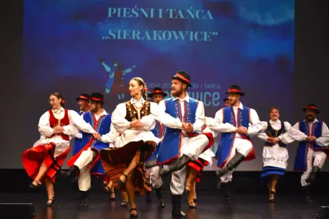 Tancerze w strojach ludowych podczas wydarzeń w Sierakowicach. Kolorowe stroje i dynamiczne ruchy na scenie.