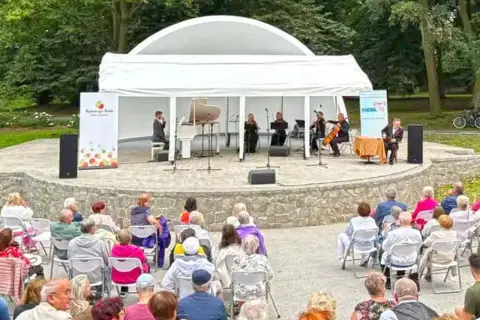 Koncert kameralny na scenie plenerowej w Kędzierzynie-Koźlu. Publiczność w różnym wieku zgromadzona na widowni.