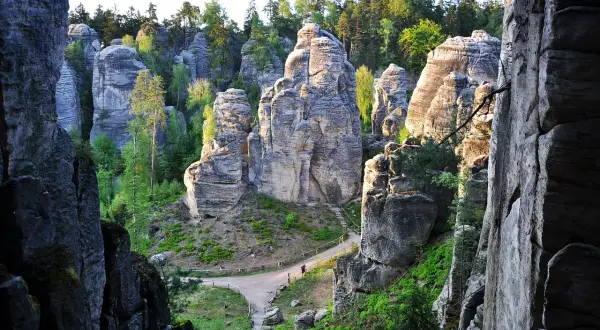 Skaliste formacje tworzą labirynty w kamiennym mieście Czech. Ścieżki wiją się między gigantycznymi skałami, otoczonymi zielenią.