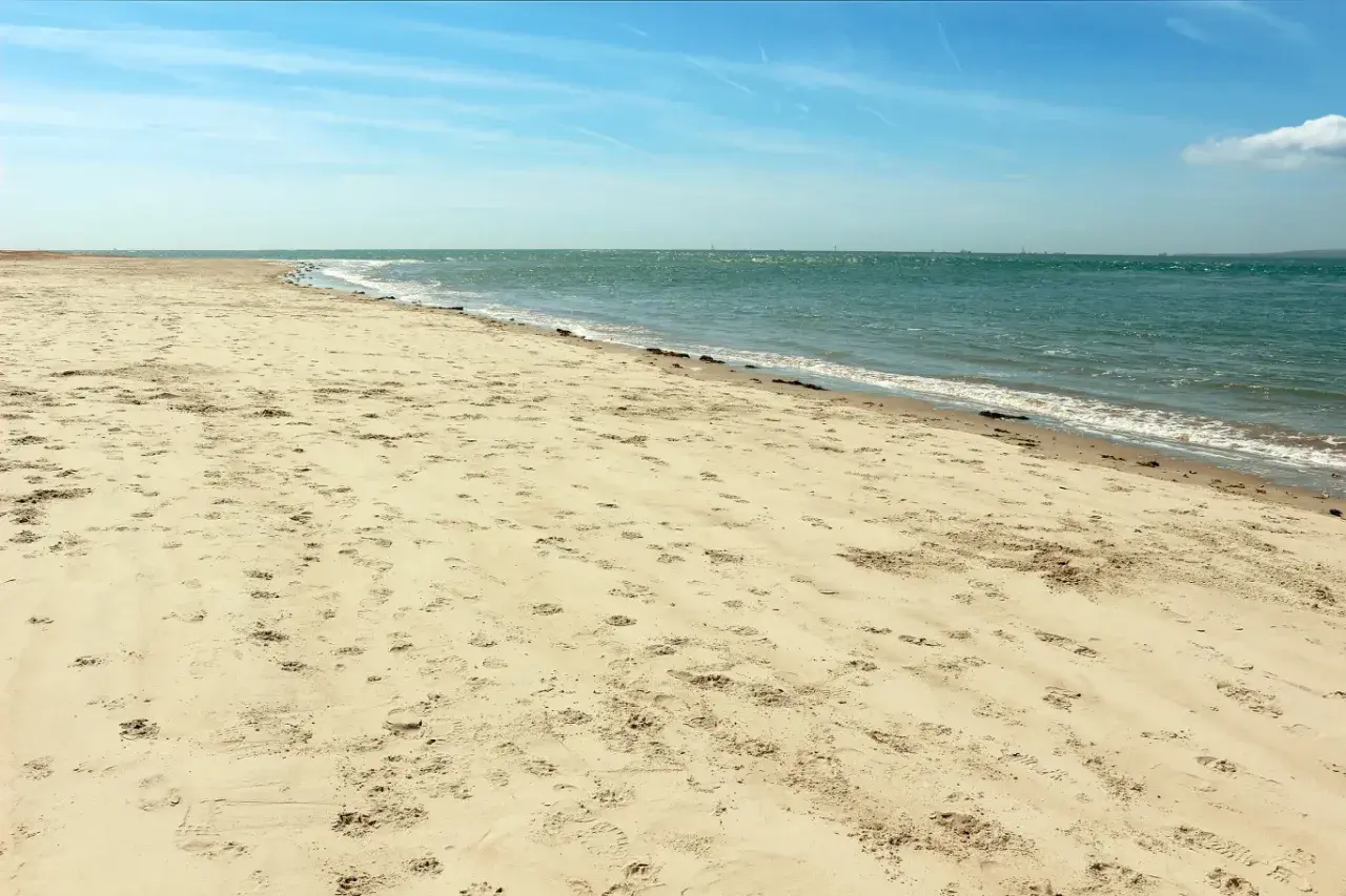 Pusta plaża Ulinia z licznymi śladami na piasku, spokojne morze i błękitne niebo.