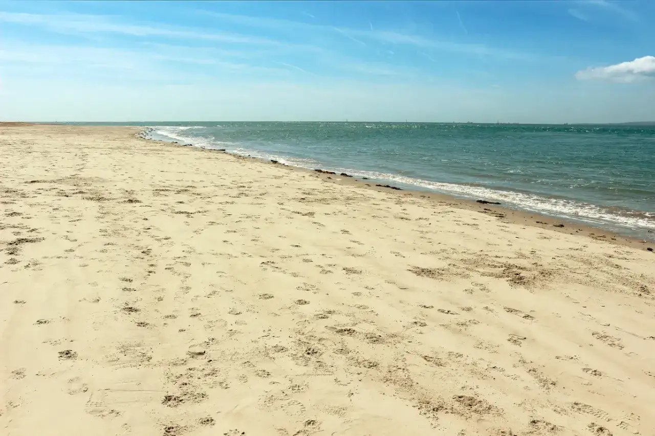 Pusta plaża Ulinia z licznymi śladami na piasku, spokojne morze i błękitne niebo.