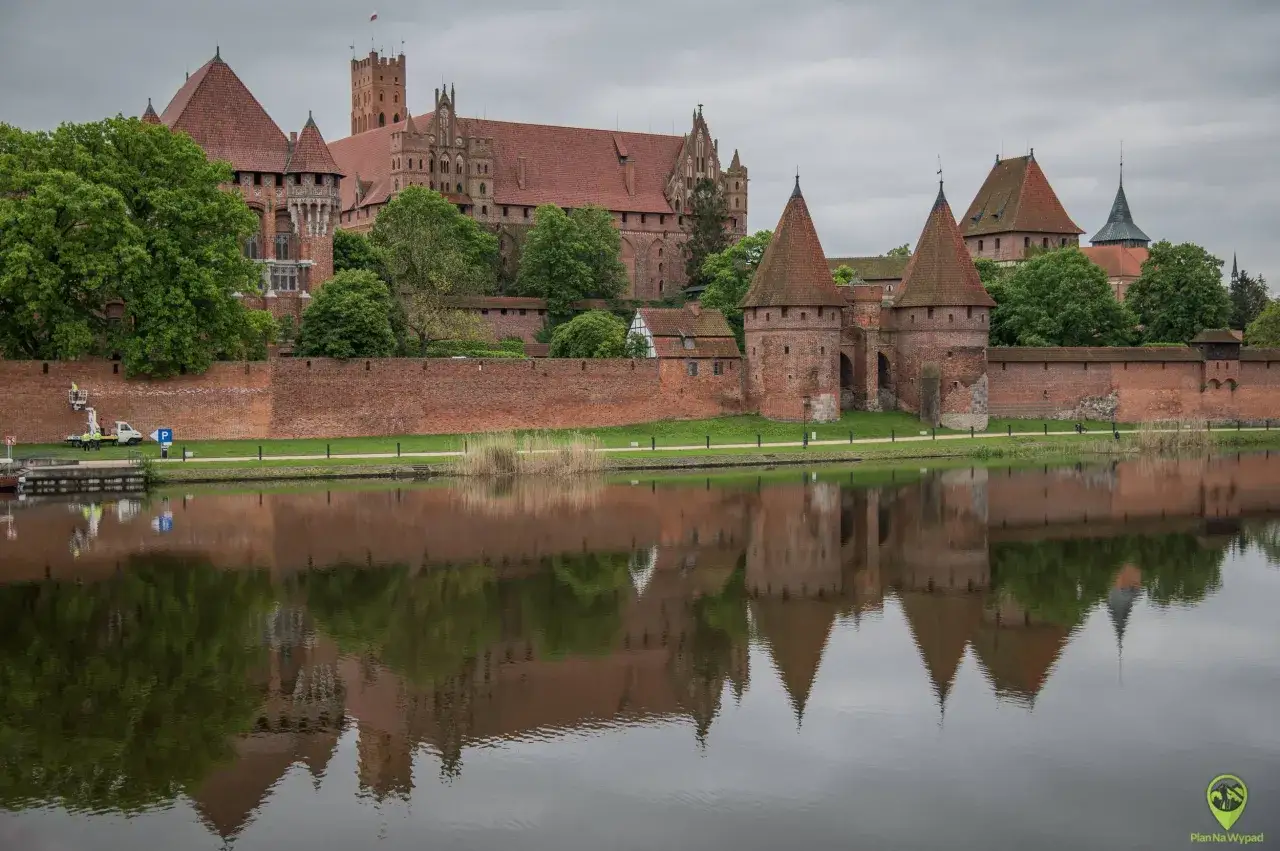 Potężny zamek w Malborku odbija się w wodzie. Sprawdź zamek w Malborku cennik i zaplanuj wizytę w tym historycznym miejscu.