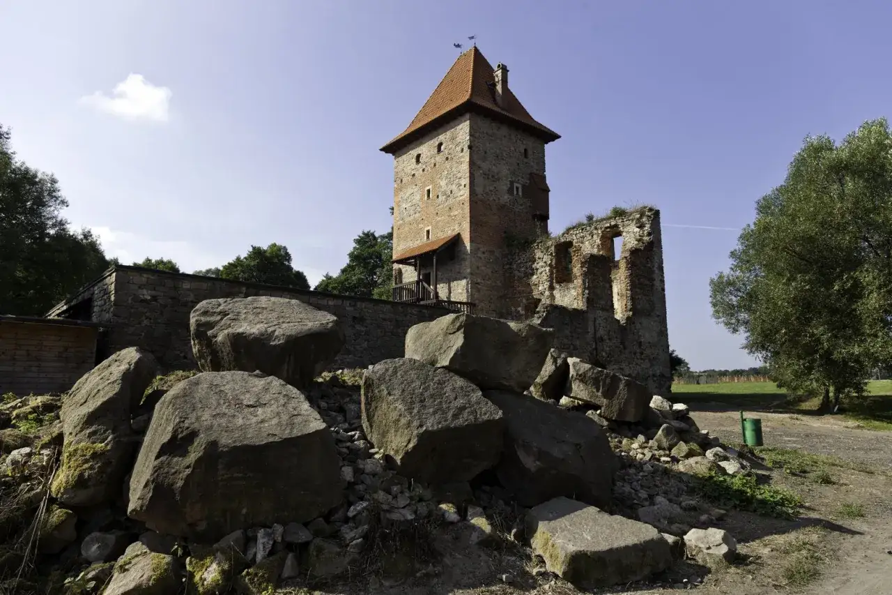 Ruiny zamku w Chudowie z wieżą i kamieniami u podnóża.