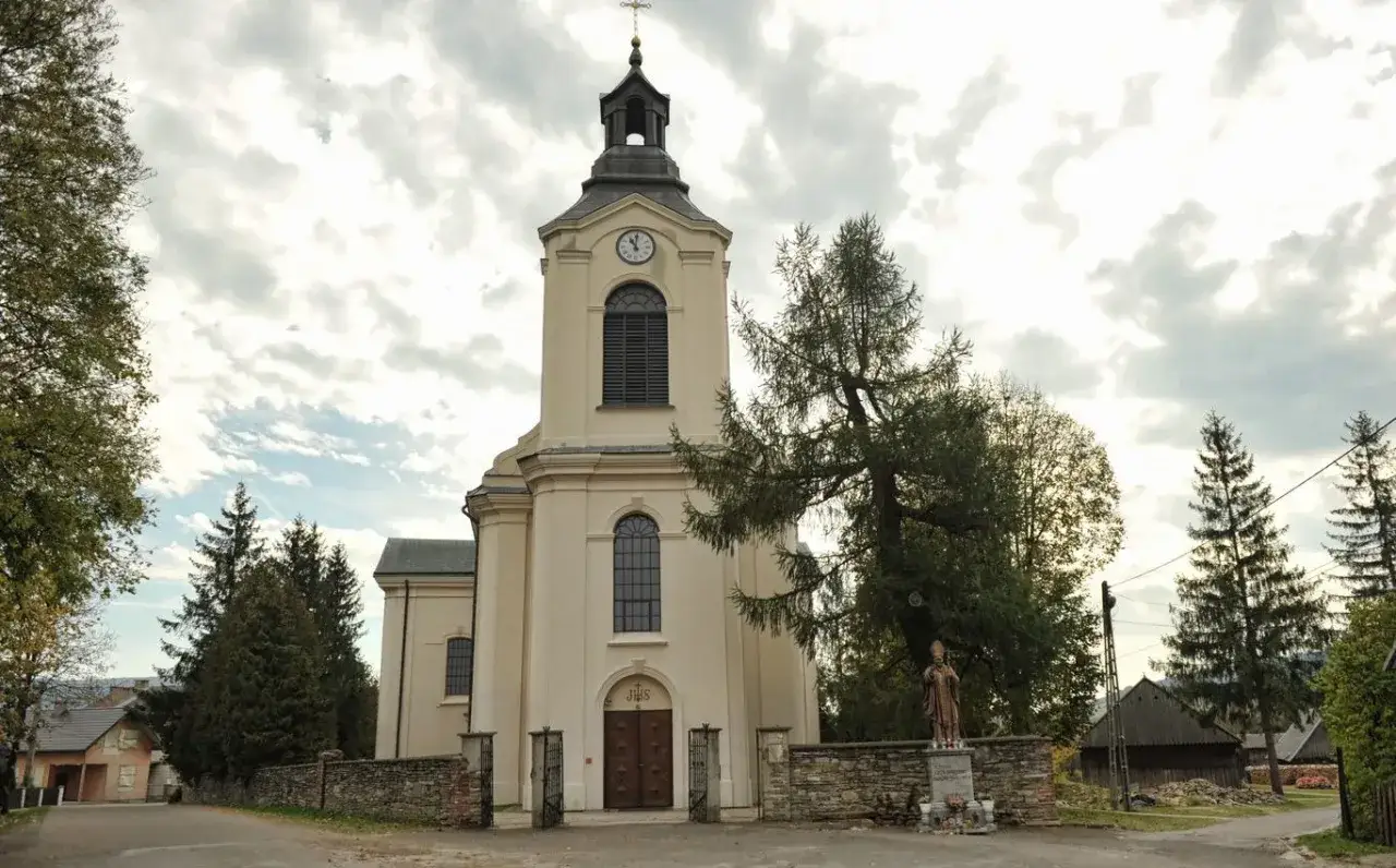 Kościół w Jaśliskach, jedna z głównych atrakcji, z wieżą zegarową i kamiennym murem.