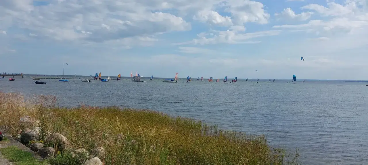 Swarzewo plaża tętni życiem. Wiele osób uprawia windsurfing i kitesurfing na spokojnych wodach.