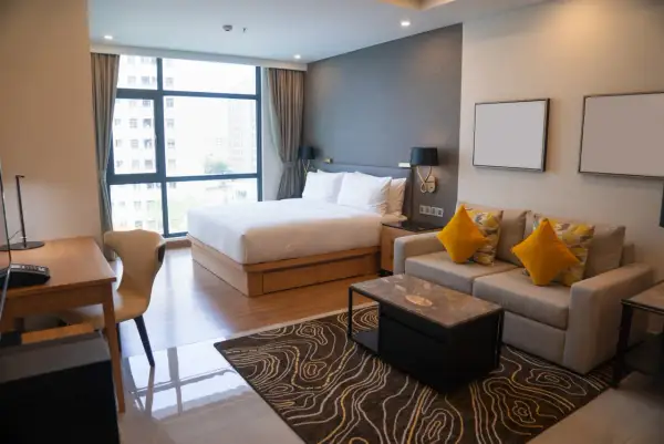 Nowoczesny pokój hotelowy z łóżkiem, sofą i biurkiem, widok z okna na miasto.