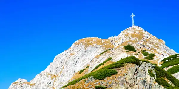 Giewont z Zakopanego, majestatyczny szczyt z krzyżem, na który wspina się grupa turystów.