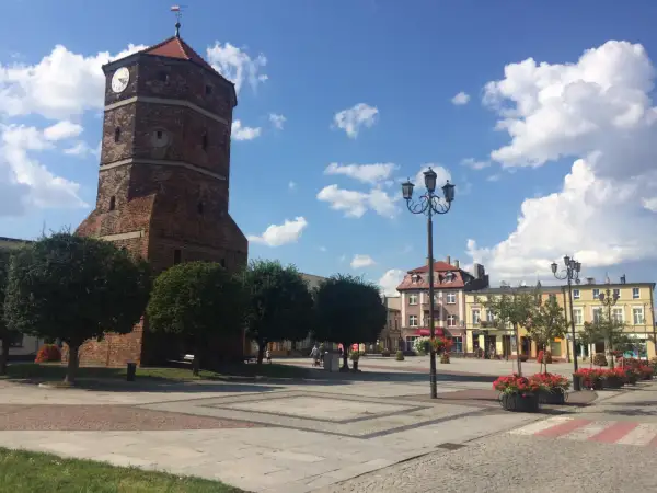 Wieża zegarowa w Barcinie góruje nad rynkiem, otoczonym kolorowymi kamienicami.