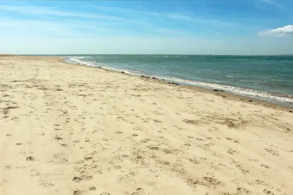 Pusta plaża Ulinia z licznymi śladami na piasku, spokojne morze i błękitne niebo.