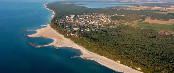Widok z lotu ptaka na nadmorską miejscowość z plażą, lasem i zatoczkami. Jezierzany atrakcje czekają!