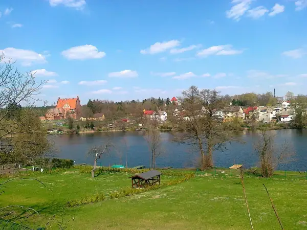 Malowniczy widok na jezioro z zamkiem i zabudowaniami w tle. Biały Bór Podkarpackie zachwyca spokojem i pięknem natury.