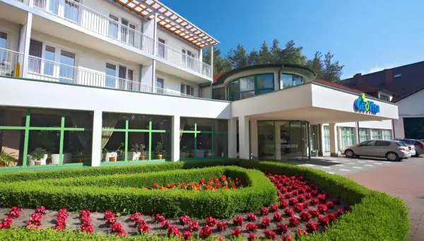 GeoVita Dąbki cennik: nowoczesny budynek hotelowy z zadbanym ogrodem i kwiatami.