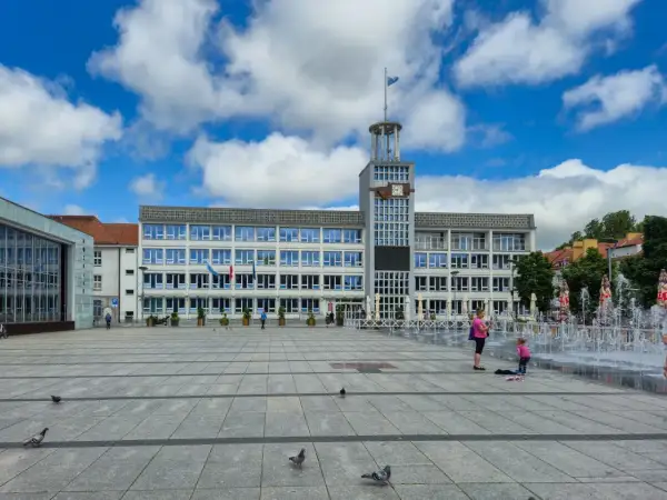 Plac miejski w Koszalinie, stare miasto, z ratuszem i fontannami w tle.